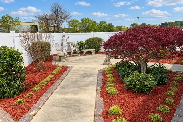 The church prayer garden with a Japanese maple, walking paths, seating, and a statue of Jesus